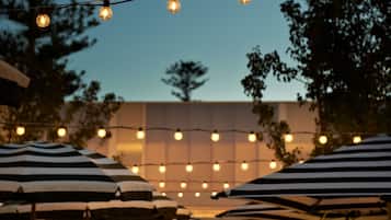 An outdoor seating area with striped umbrellas and string lights.