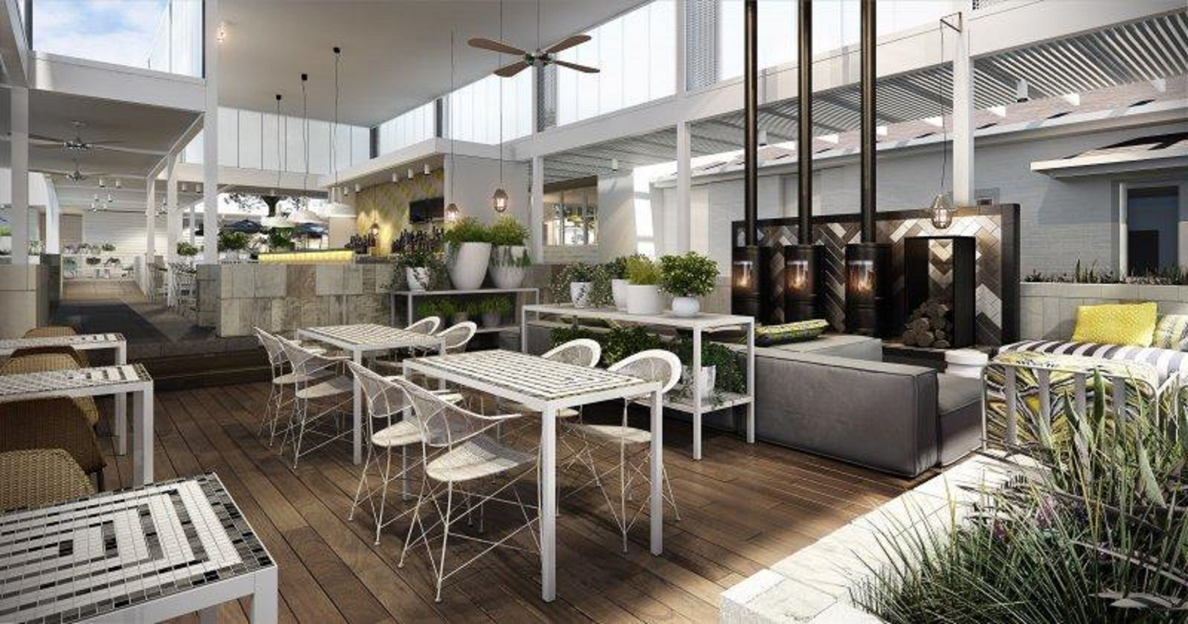 A spacious indoor area with high ceilings, a central seating area with tables and chairs, and a kitchen area with modern appliances.