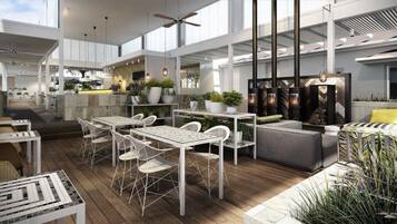 A spacious indoor area with high ceilings, a central seating area with tables and chairs, and a kitchen area with modern appliances.