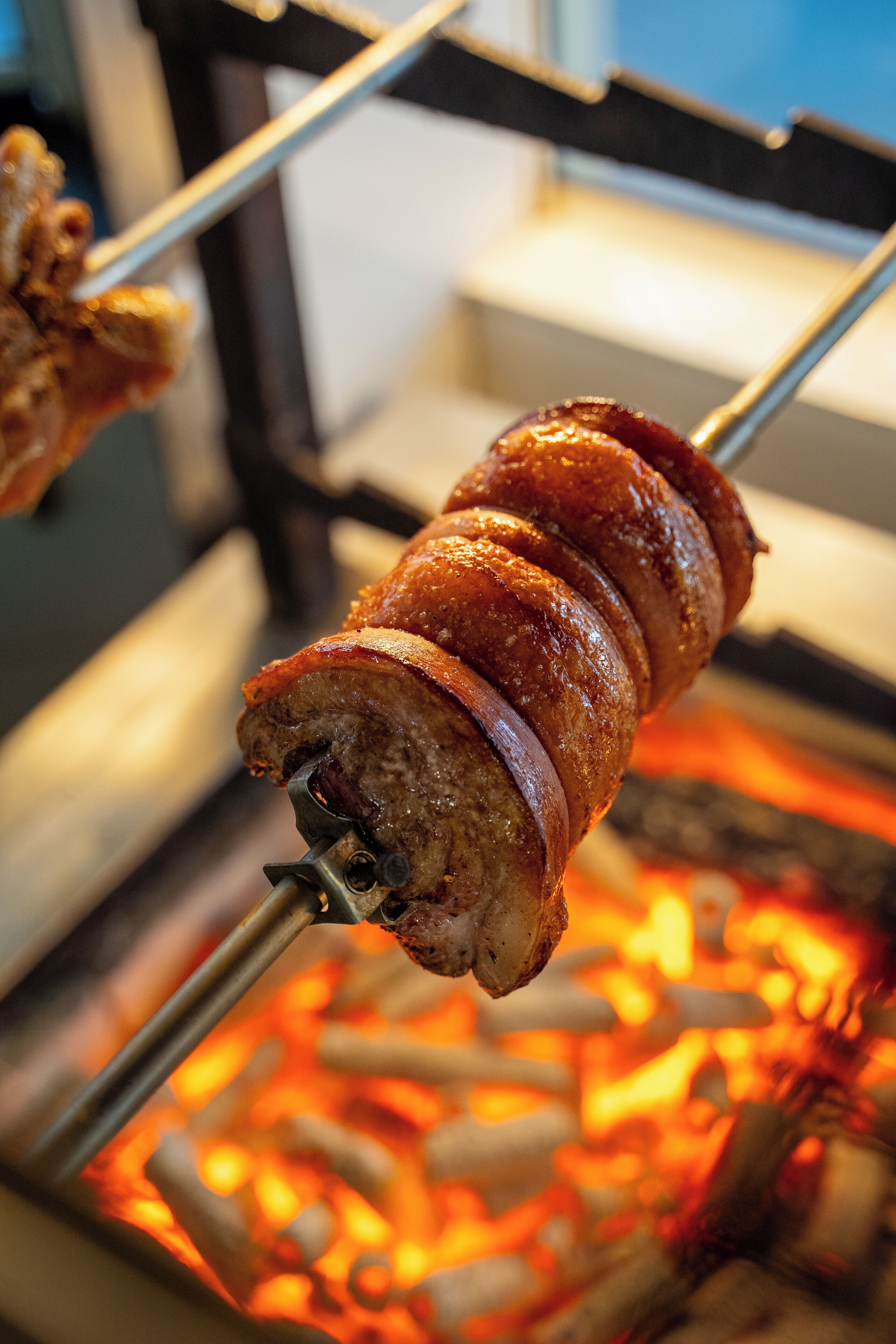 A skewered meat being cooked over an open flame.