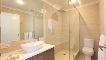 A modern bathroom with a glass-enclosed shower, a white sink, and a toilet.