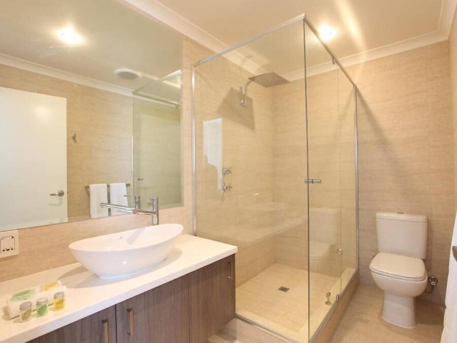 A modern bathroom with a glass-enclosed shower, a white sink, and a toilet.