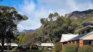 A residential area with a grassy lawn, a gazebo, and a building with solar panels. - Pinnacle Holiday Lodge (Halls Gap)