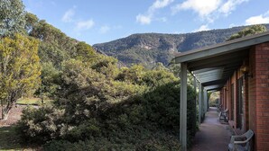 A covered walkway with benches, surrounded by dense shrubbery and a mountain backdrop. - Pinnacle Holiday Lodge (Halls Gap)