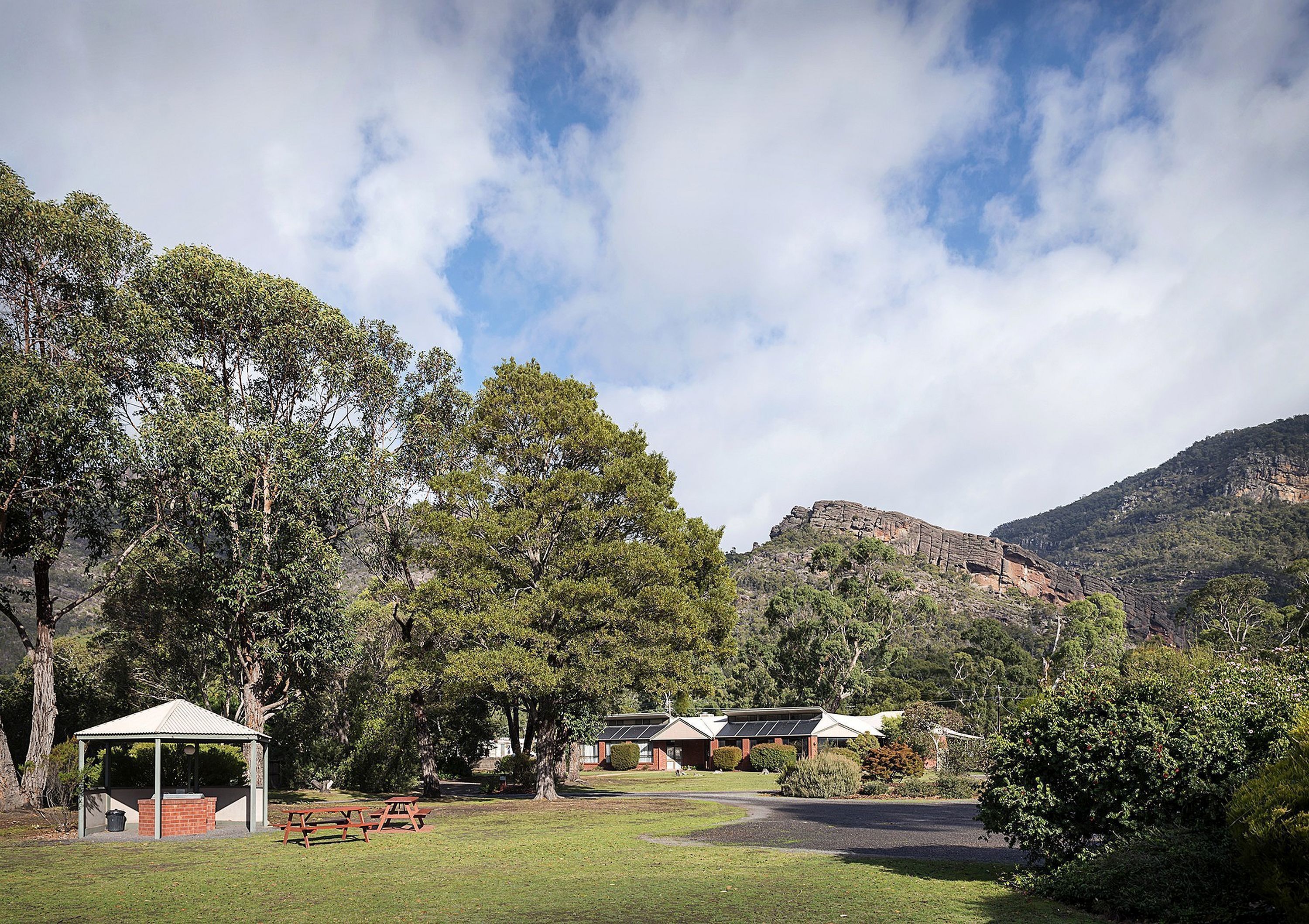A park with picnic tables, a gazebo, and buildings with solar panels.