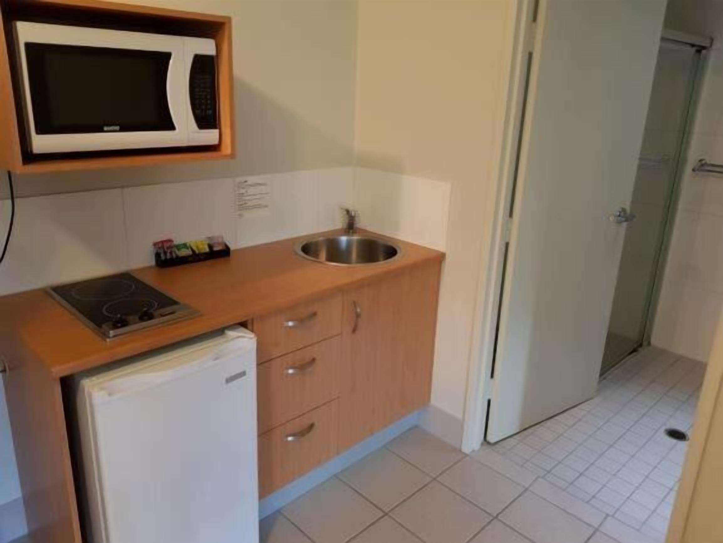 Una cocina compacta equipada con microondas, fregadero, cocina y refrigerador.