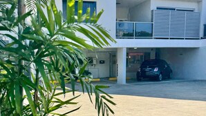 Un hôtel moderne doté d’une réception et d’un espace de stationnement, d’un parking couvert et offrant une vue sur un ciel dégagé.