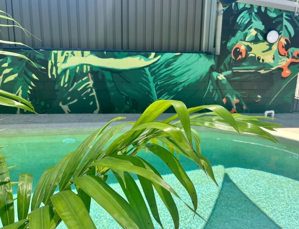 A swimming pool with clear water and a mural of a jungle scene on the wall behind.