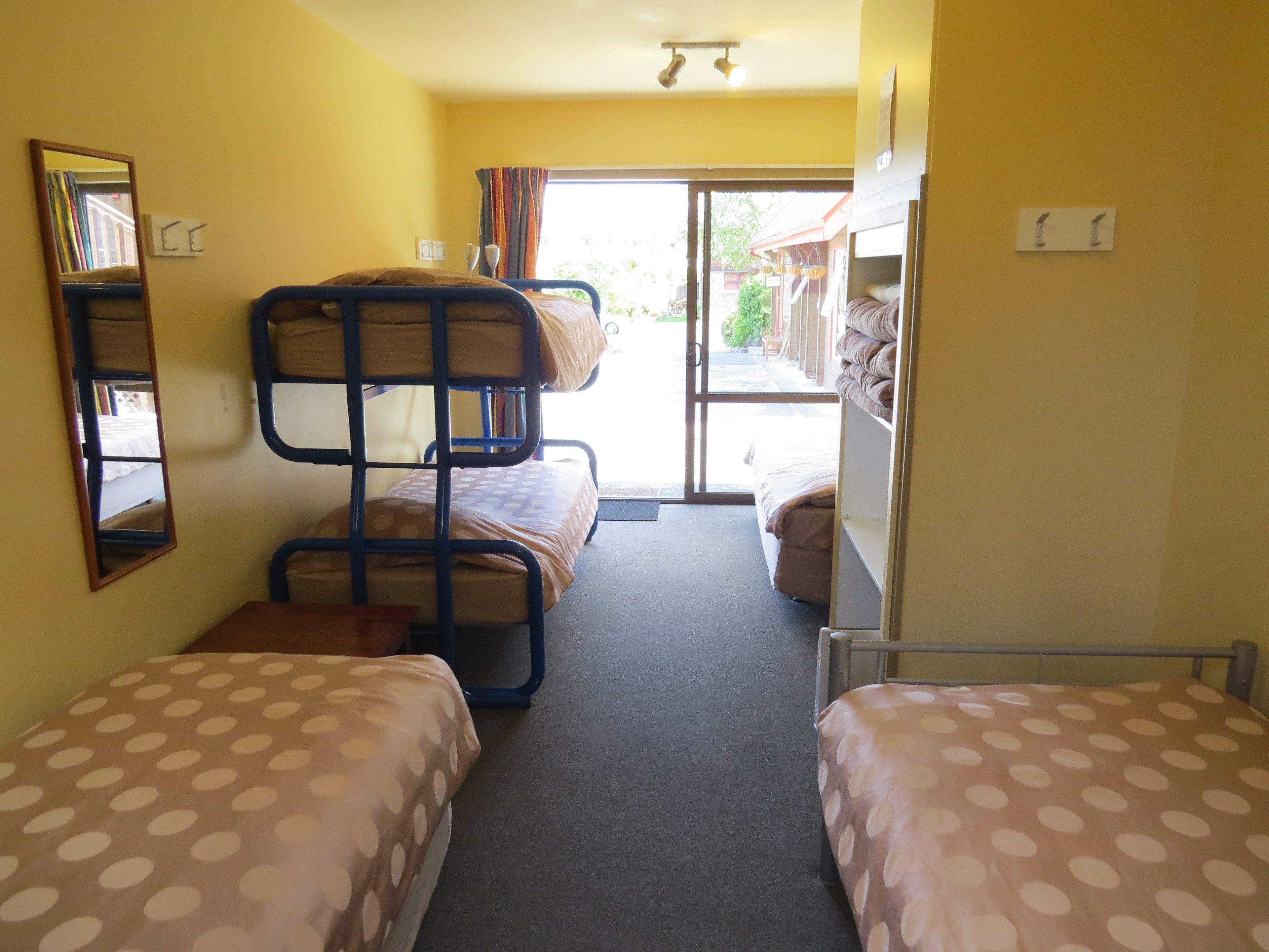 A room with bunk beds, a small table, and a mirror.