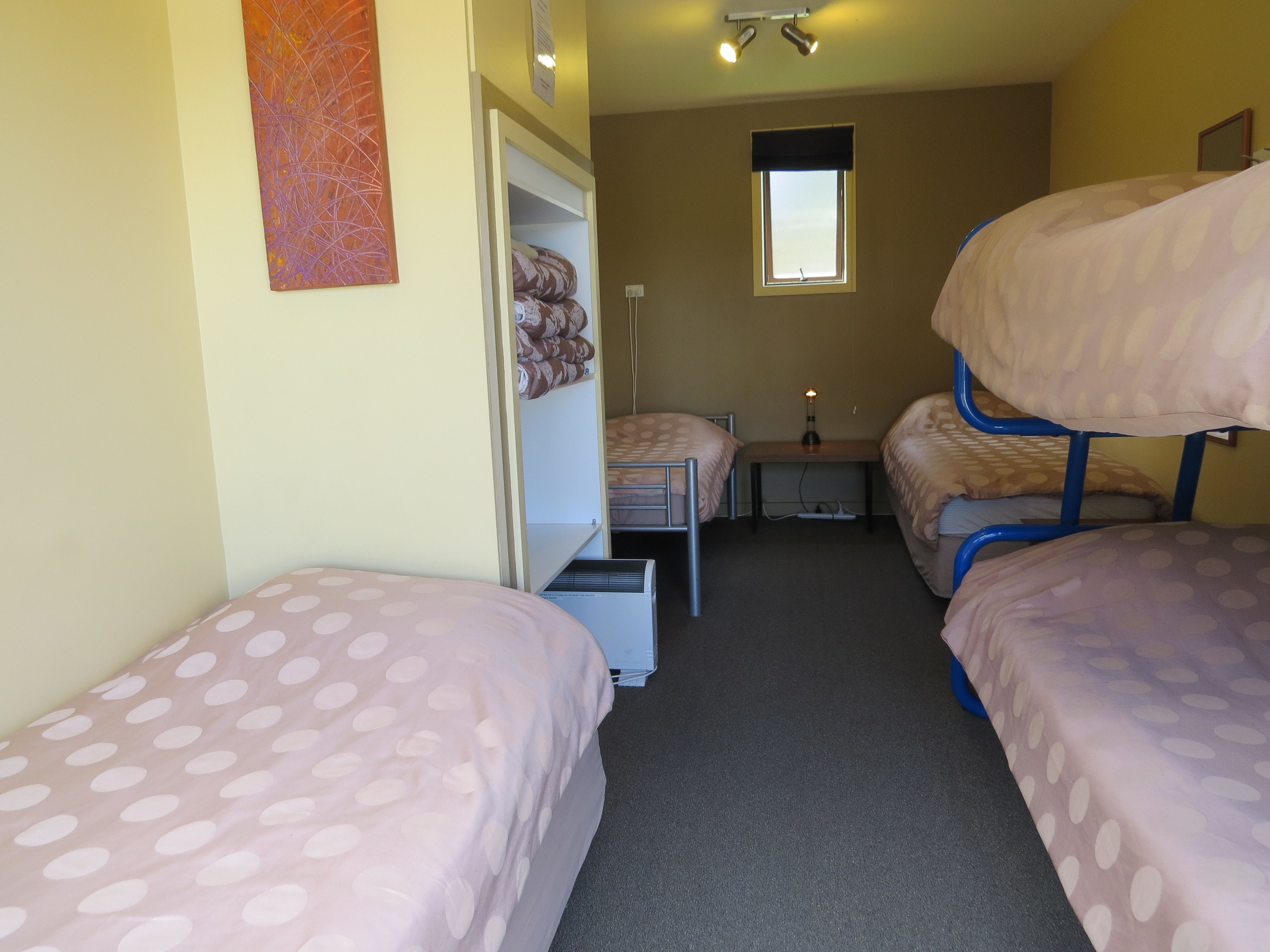 A dormitory room with bunk beds, a desk, and a window.