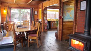 Un interior de madera con una mesa redonda y sillas, una chimenea y un mapa en la pared.