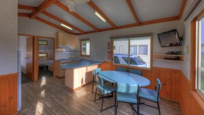 A compact kitchen with wooden cabinets, a central island, and a dining area with chairs.