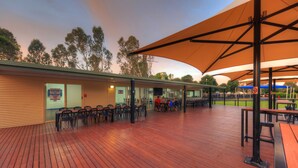 An outdoor seating area with wooden flooring and tables under large umbrellas.