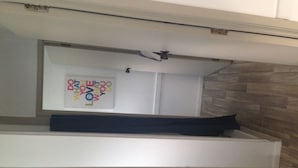 A room with a bed, a ceiling fan, and a wall-mounted artwork. - Whitianga Campground (Whitianga)