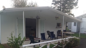 A mobile home with a porch, outdoor seating, and a small garden area. - Whitianga Campground (Whitianga)