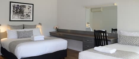 Una habitación de hotel moderna con dos camas, un espejo grande, un escritorio con una silla y una obra de arte colgada en la pared.