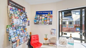 A desk with a red chair, a visitor information board, and a closed sign on the window. - Ascot Vale Motor Lodge (Christchurch)