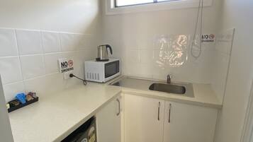 A small kitchenette with a microwave, a kettle, a sink, and a 'No Smoking' sign.