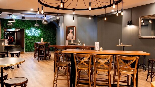 A restaurant with wooden tables and chairs, a green wall, and a circular light fixture. - Campaspe Lodge Echuca (Echuca)