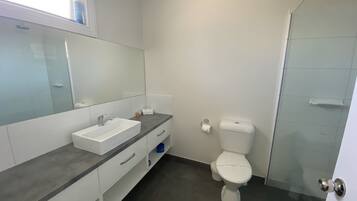 Baño con lavamanos, espejo y retrete blancos.