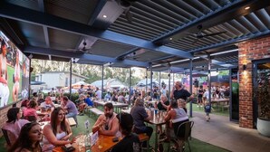 An outdoor dining area with tables and chairs, a brick wall, and a large mural on the left. - Campaspe Lodge Echuca (Echuca)