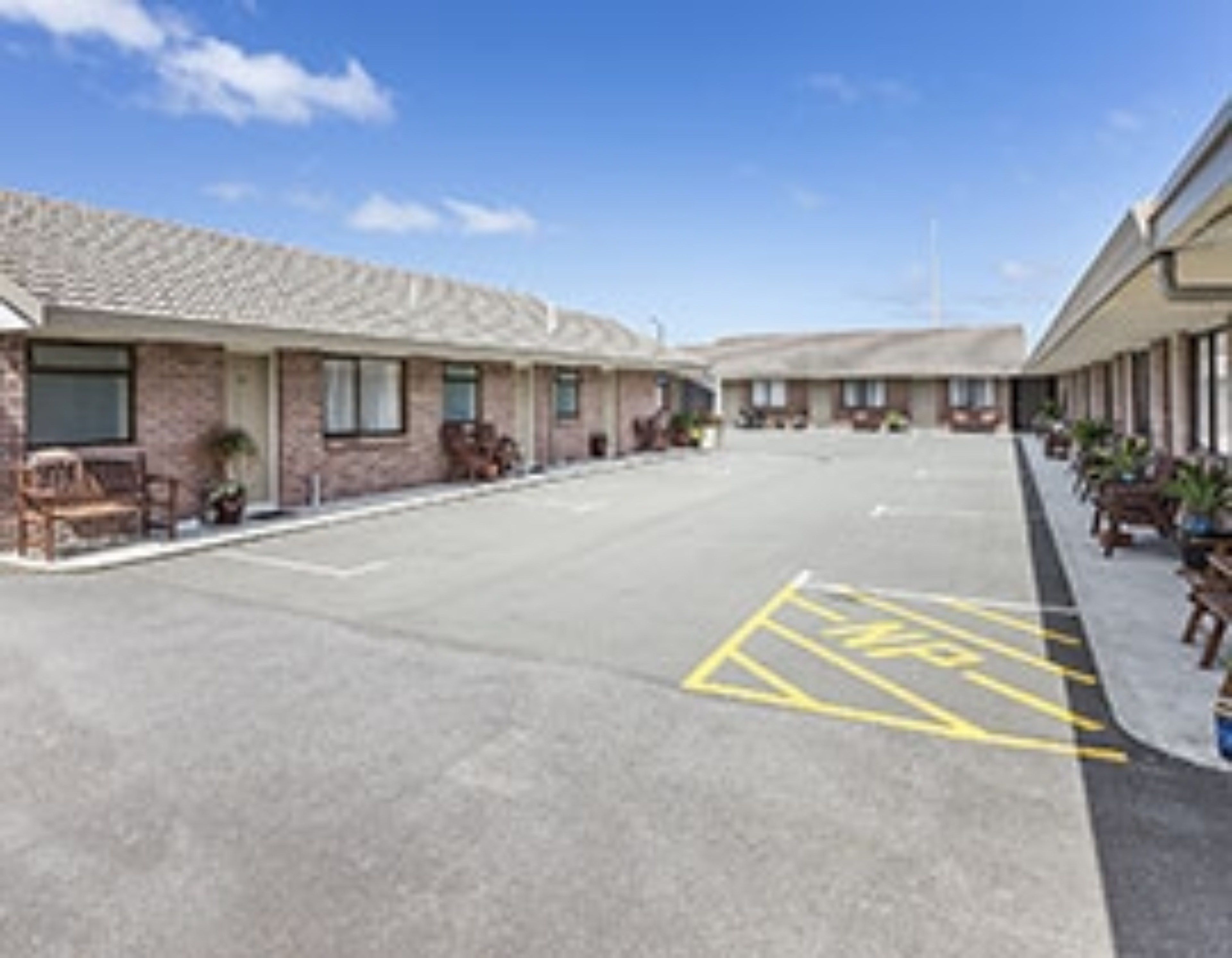 A motel with a parking lot marked with a handicap parking symbol.