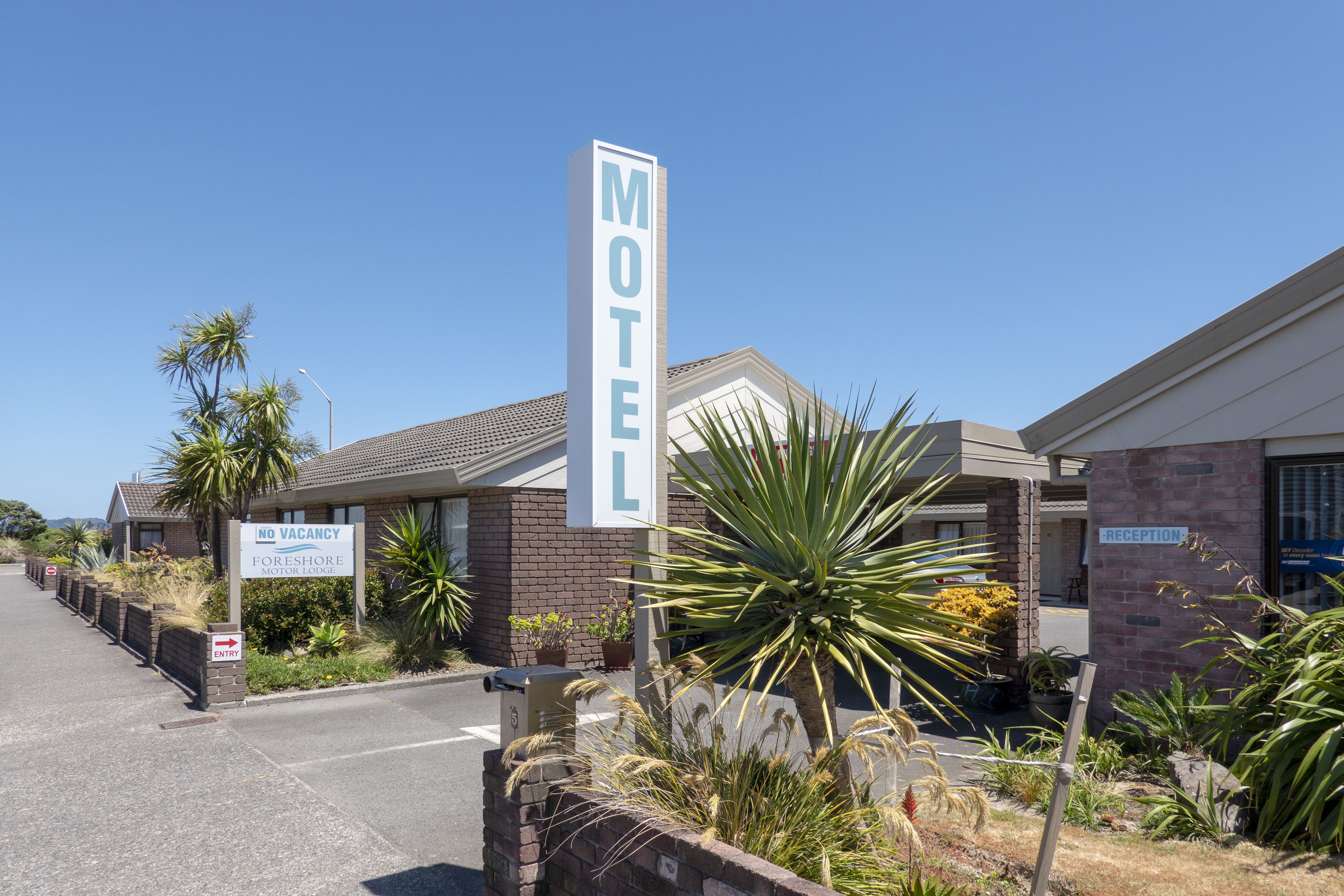 A motel with a 'No Vacancy' sign, a reception area, and a parking lot.