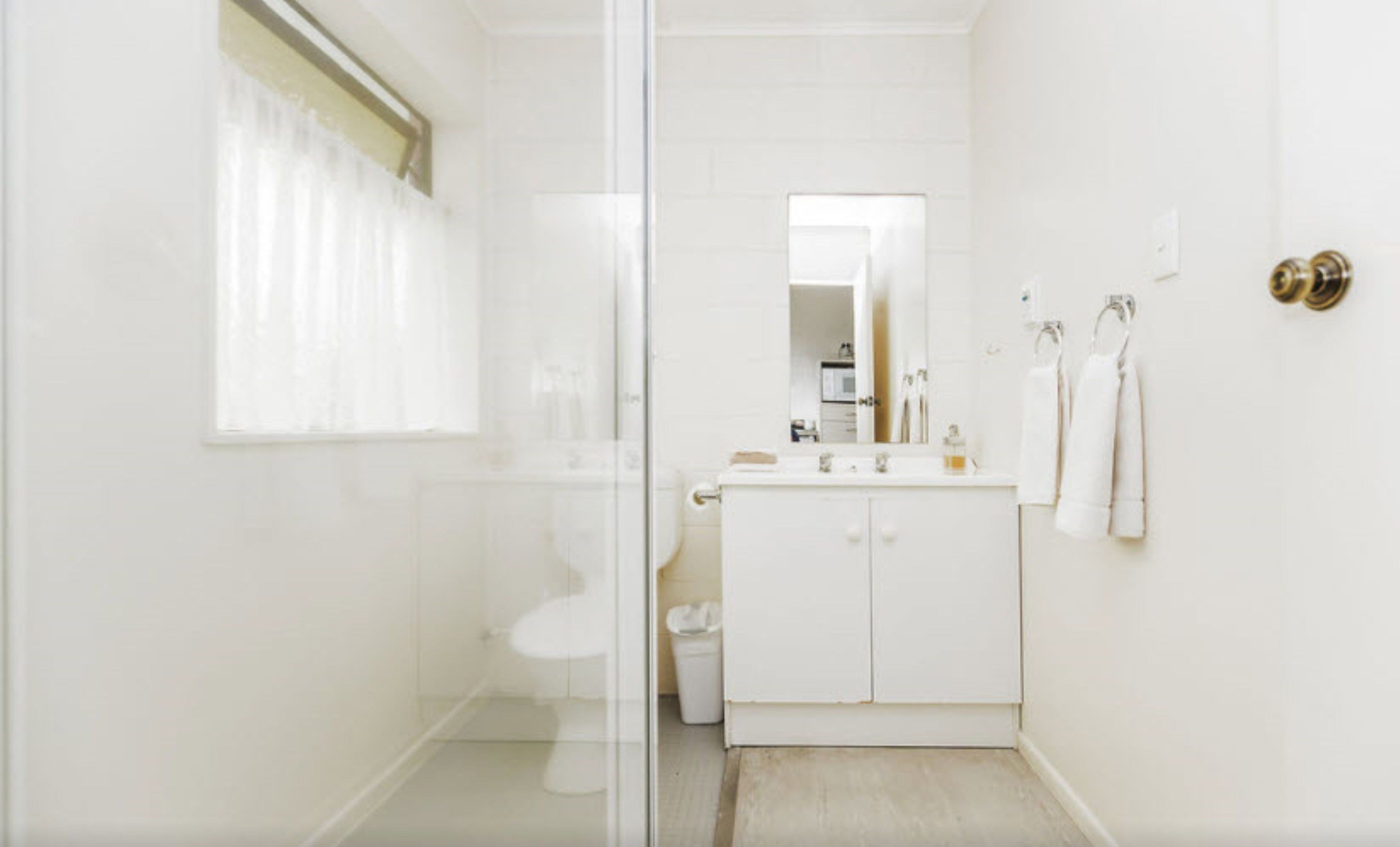 A modern bathroom with a glass shower enclosure, a white sink with a mirror above it, and a toilet.