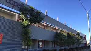 Un hotel con un diseño arquitectónico moderno, que destaca por su techo plano y una serie de balcones.