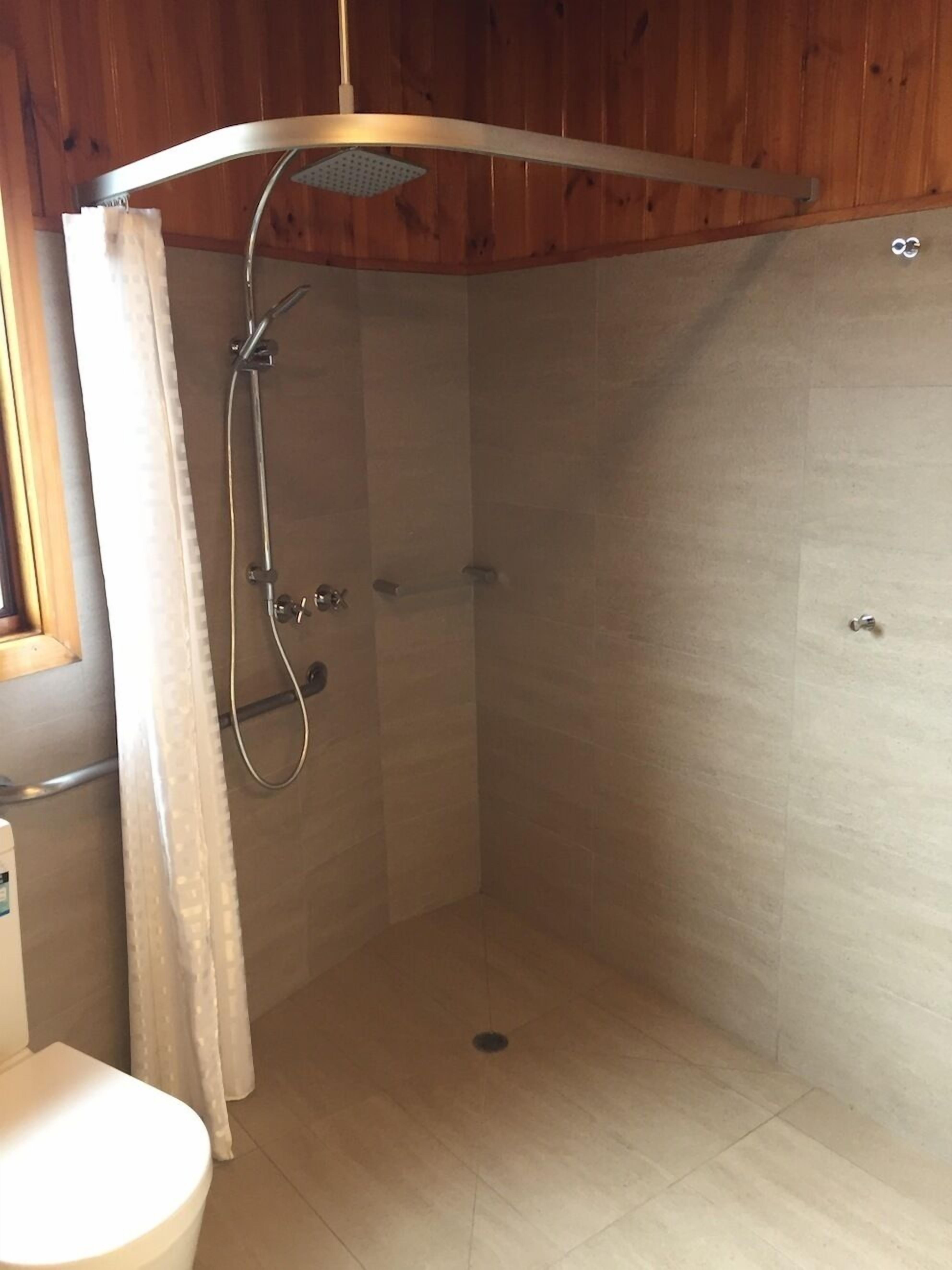 A shower with a curved ceiling, a showerhead, and a curtain.
