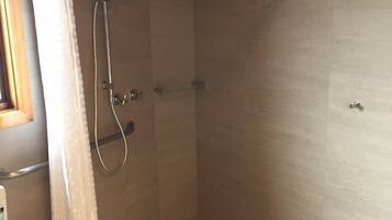 A shower with a curved ceiling, a showerhead, and a curtain.