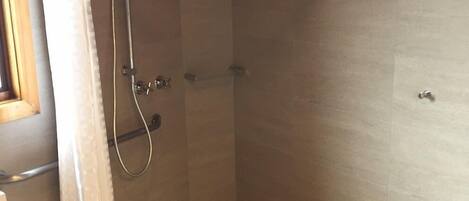 A shower with a curved ceiling, a showerhead, and a curtain.