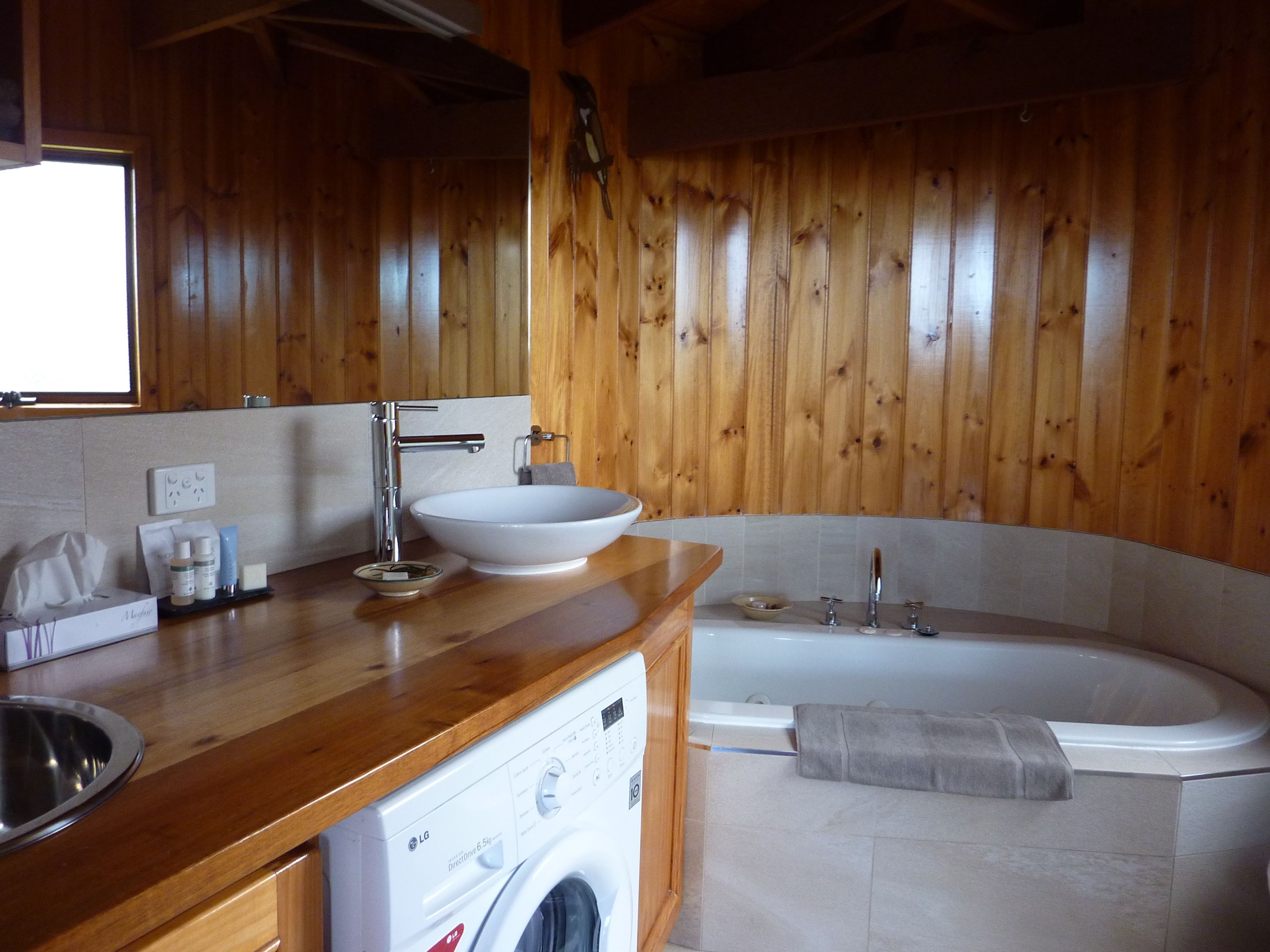 Een houten interieur met een wastafel, wasmachine en bad.