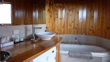 Een houten interieur met een wastafel, wasmachine en bad.