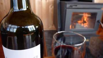 Uma garrafa de vinho Baía dos Apóstolos e um copo de vinho tinto sobre uma mesa de madeira.
