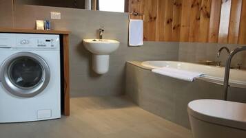Een moderne badkamer met een wasmachine, wastafel en bad.
