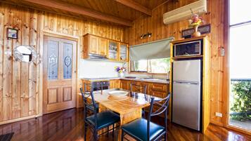 A wooden interior with a dining table, chairs, a refrigerator, and wooden cabinets.