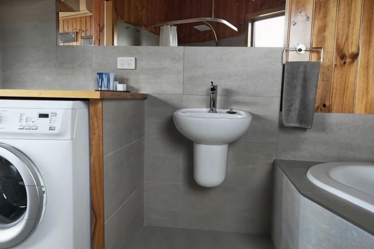 Un baño pequeño con lavadora, lavamanos y bañera.