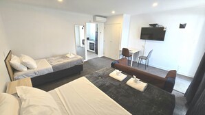Una camera d'albergo con un letto, un divano, una scrivania e una televisione.