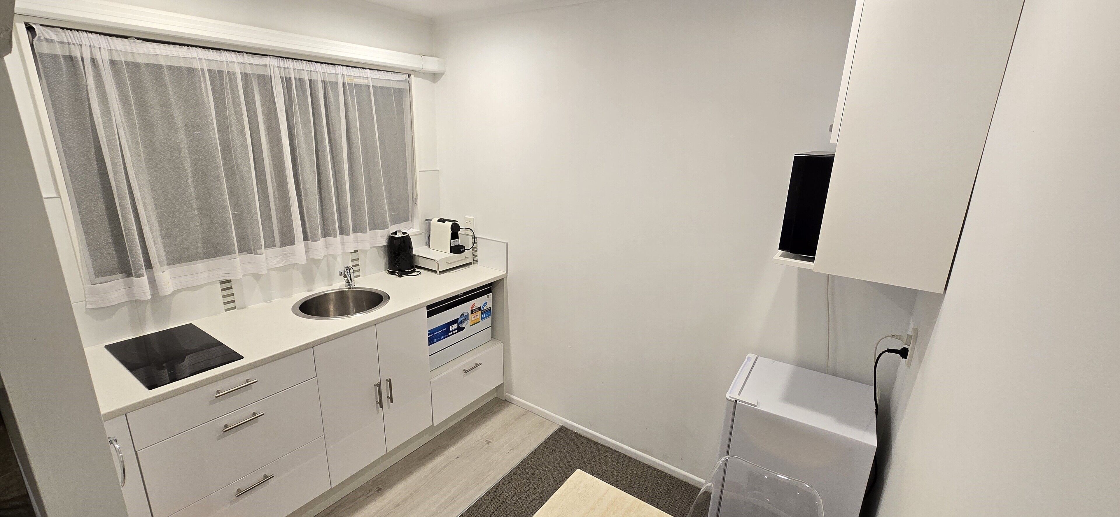 A compact kitchen with a sink, a coffee maker, and a microwave.
