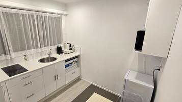 A compact kitchen with a sink, a coffee maker, and a microwave.