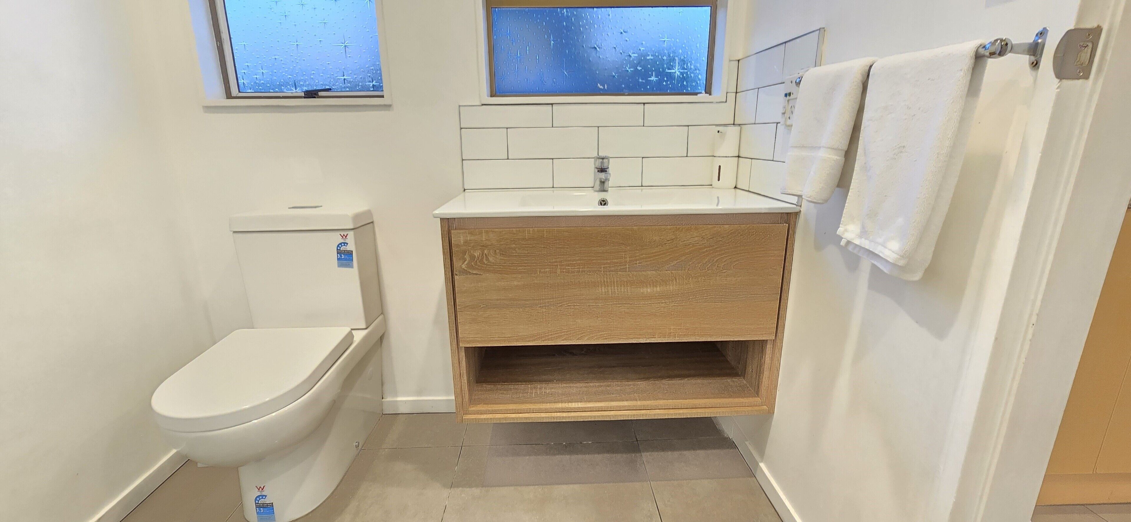 Une petite salle de bain compacte, équipée de toilettes, d’un lavabo et d’un miroir placé au-dessus.