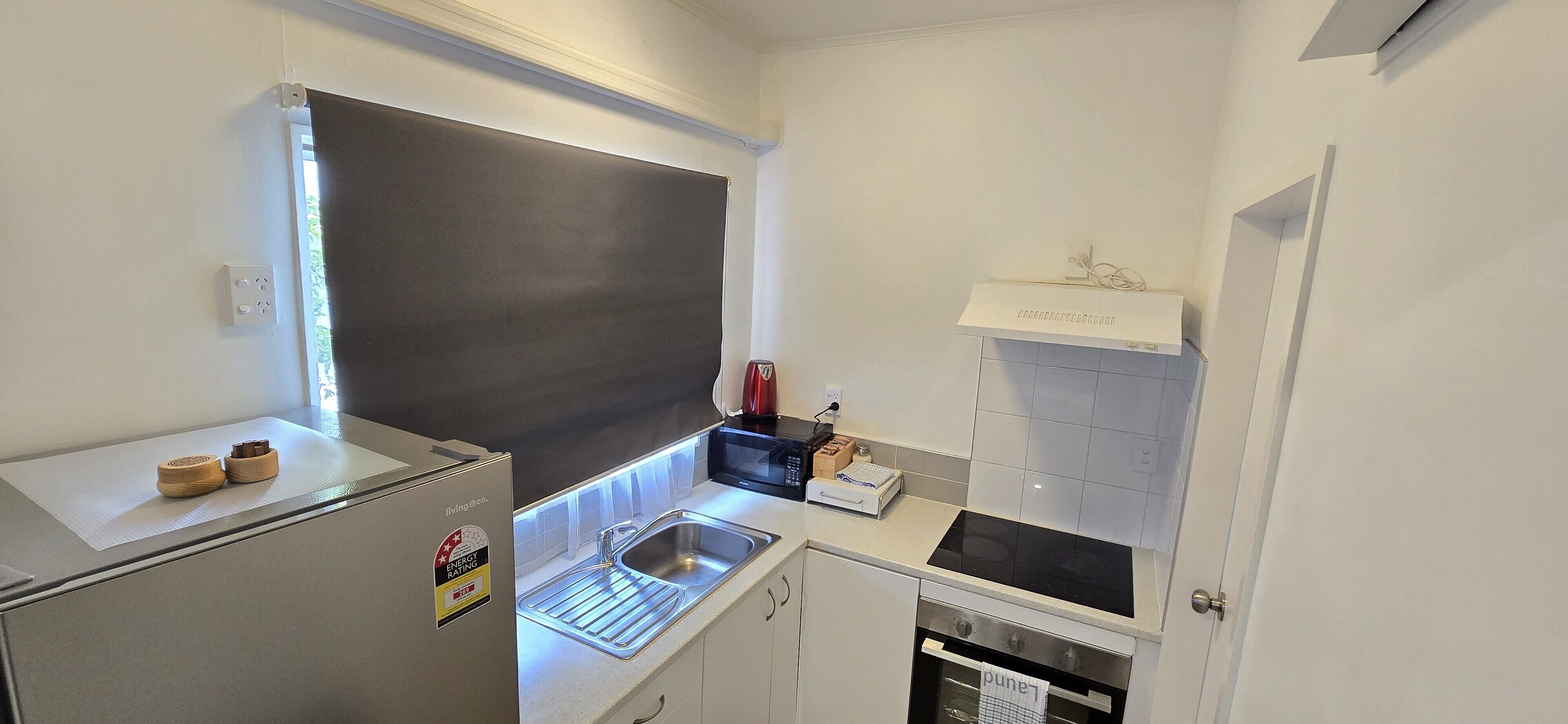 A compact kitchen with a refrigerator, sink, stove, and microwave.