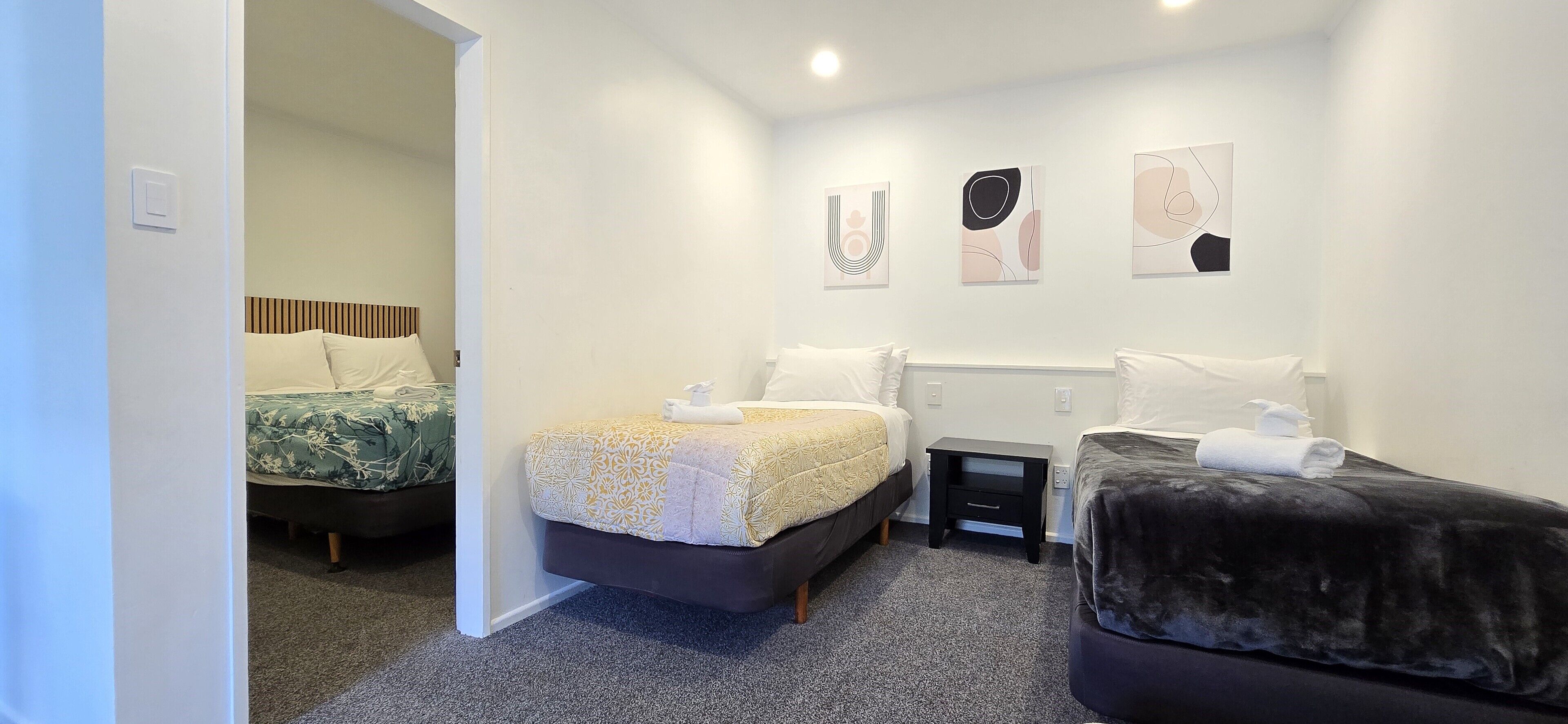 Une chambre d’hôtel avec deux lits, une petite table de chevet et des œuvres d’art accrochées au mur.