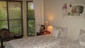 A bedroom with a large bed, a chair, a nightstand, and a window with curtains. - Beechworth Gorge Walk Guest House (Beechworth)