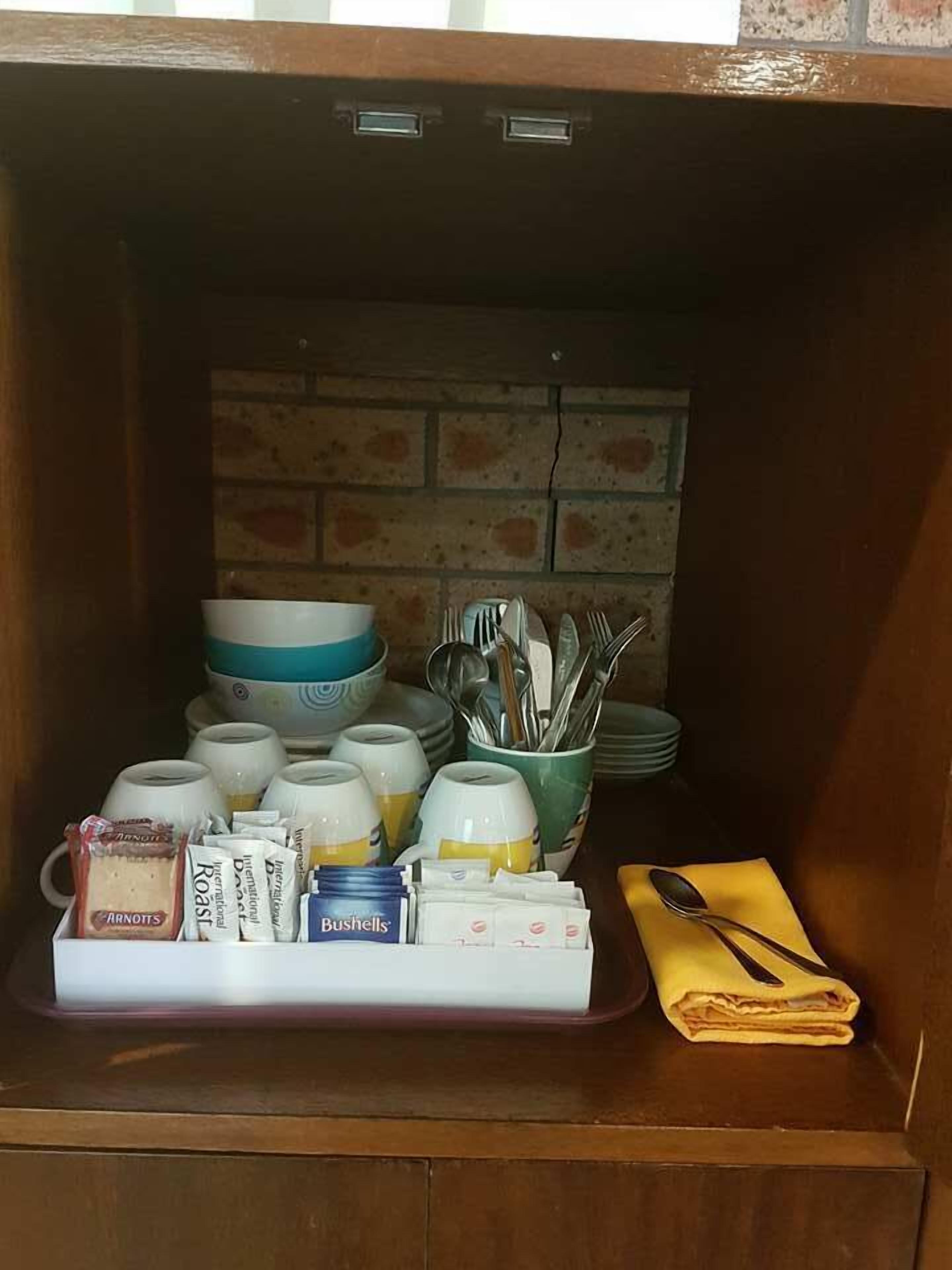 A kitchen cabinet with various kitchenware and food items.