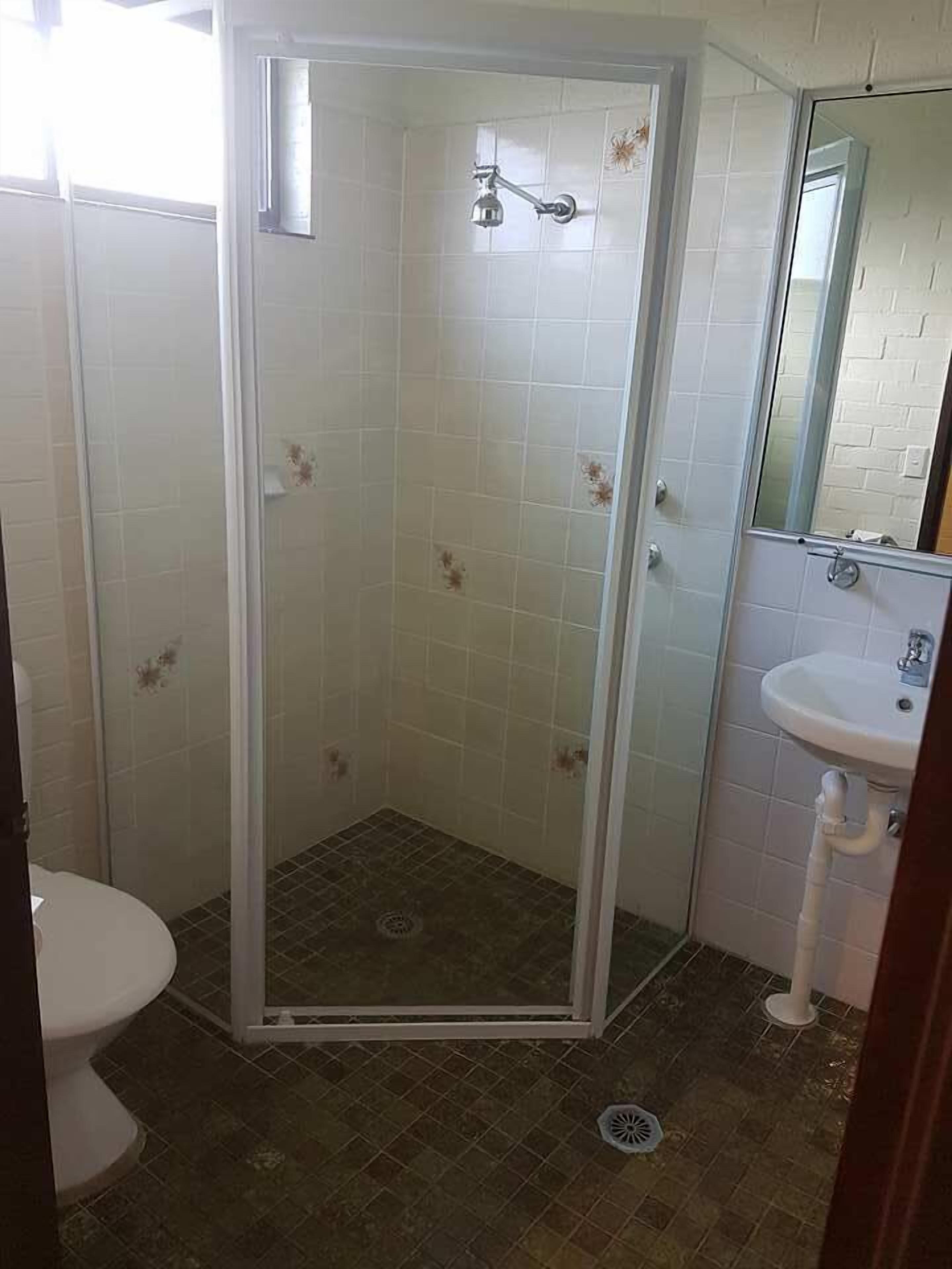 A bathroom with a glass-enclosed shower, a white sink, and a toilet.
