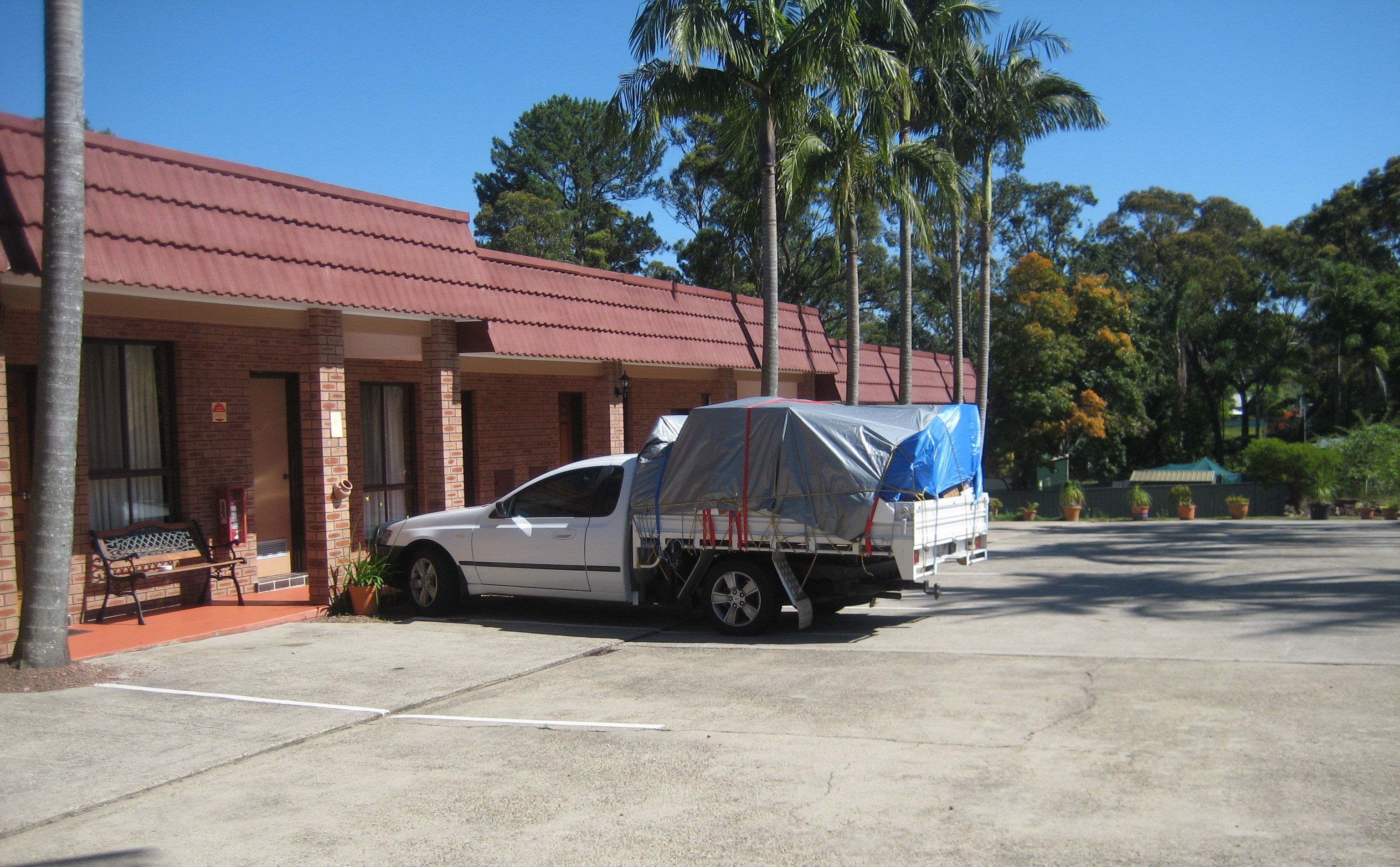 A white pickup truck parked in front of a building with a red roof and brick walls.