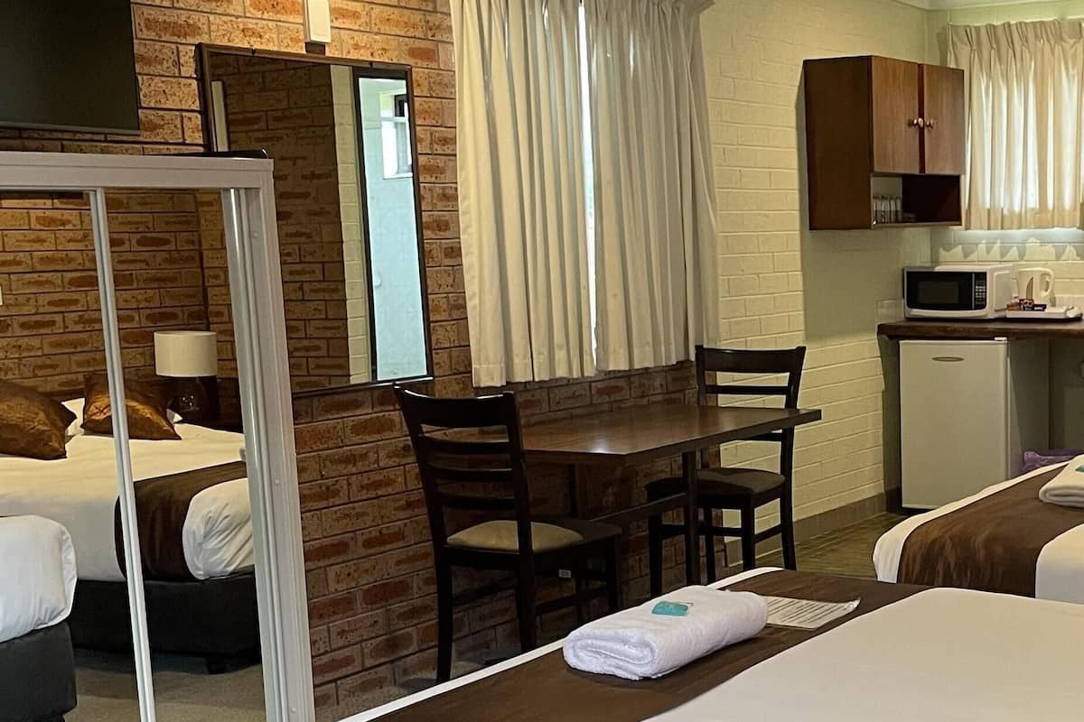 Ein Hotelzimmer mit einem großen Bett, einem Schreibtisch, einem Sessel, einer kleinen Kühlbox und einem Spiegel.
