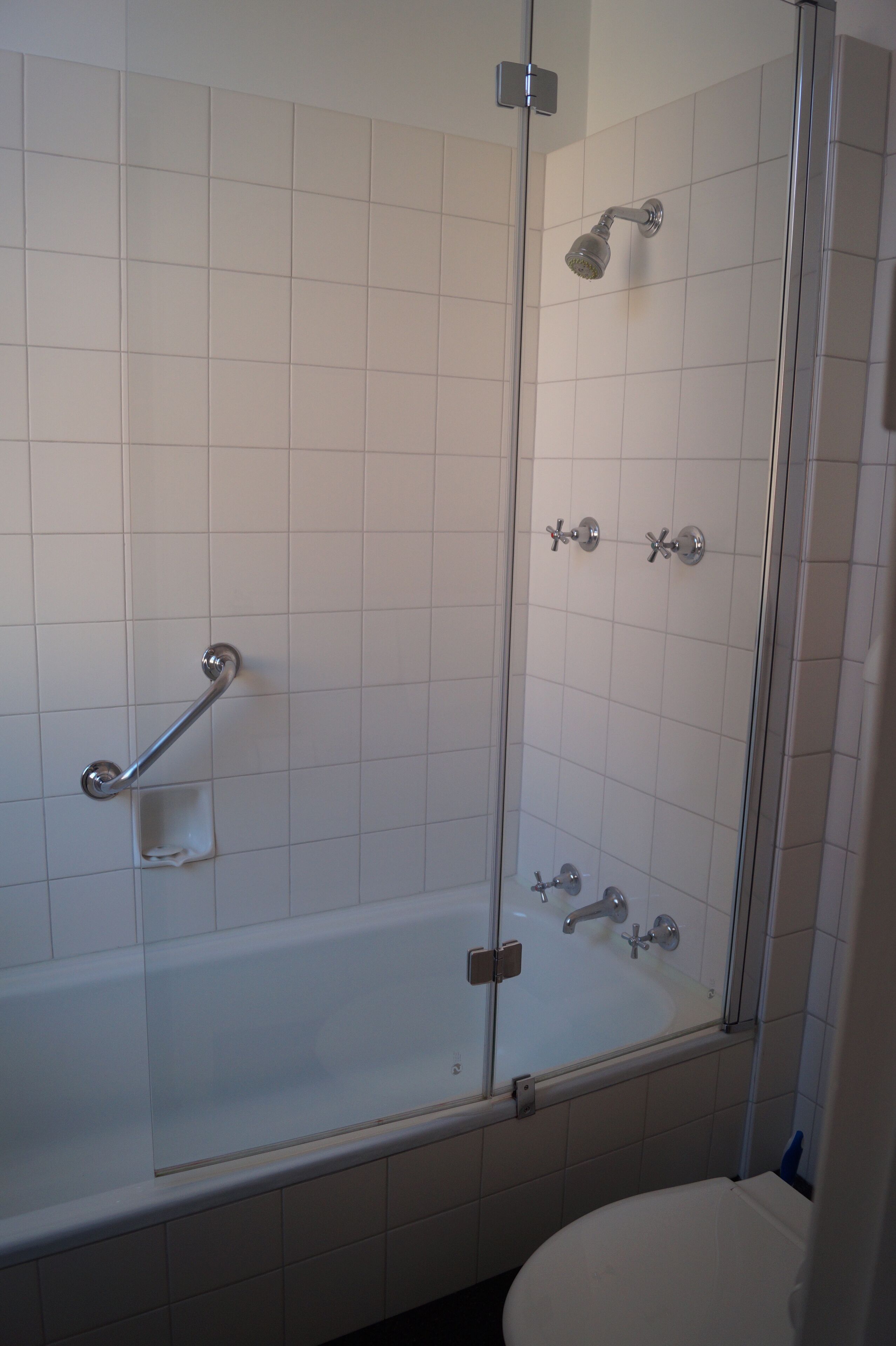 A bathroom with a glass-enclosed shower, a white bathtub, and a white toilet.